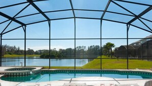 A pool area with a view of a lake, surrounded by a glass enclosure. - Orlando Renters (Davenport)