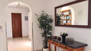 A hallway with a wooden console table, a potted plant, a mirror, and a door leading to another room. - Luxury 3-Bedroom Villa with Private Pool in Los Mojones, Puerto del Carmen (VV) (Puerto del Carmen)