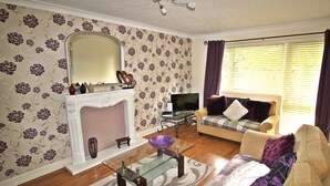 A living room with a fireplace, sofa, and television. - Balcony Apartment - Spacious 2 Large Beds (Doncaster)
