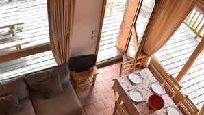 A cozy living room with a sofa, a dining table set for two, and a TV on a stand.