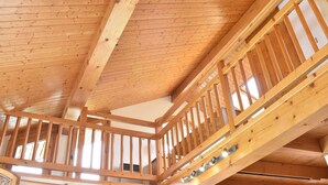 A wooden interior with a high ceiling and a wooden staircase.