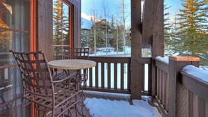 A wooden deck with a table and chairs, overlooking a snowy landscape with trees and a mountain in the background. - Luxurious 2 Bedroom0 Feet From The Slopes! Condo by RedAwning (Avon)