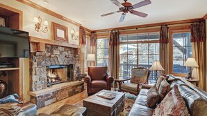 A cozy living room with a stone fireplace, leather furniture, and large windows with curtains. - Luxurious 2 Bedroom0 Feet From The Slopes! Condo by RedAwning (Avon)