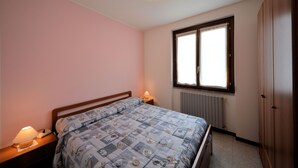 Een slaapkamer met een bed, bedlampen, een raam en een radiator.