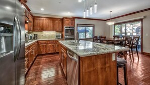 A modern kitchen with wooden cabinets, stainless steel appliances, a granite countertop, and a large island. - Tahoe Woods #602 Walk to Gondola, Lake, Casinos (South Lake Tahoe)