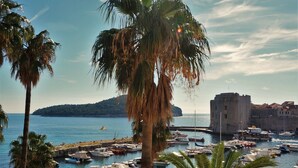 A marina with boats docked, palm trees, and a castle-like structure in the background. - PENDO 3 apartment with 4 bedrooms, sea view, close to beaches and Dubrovnik (Mlini)