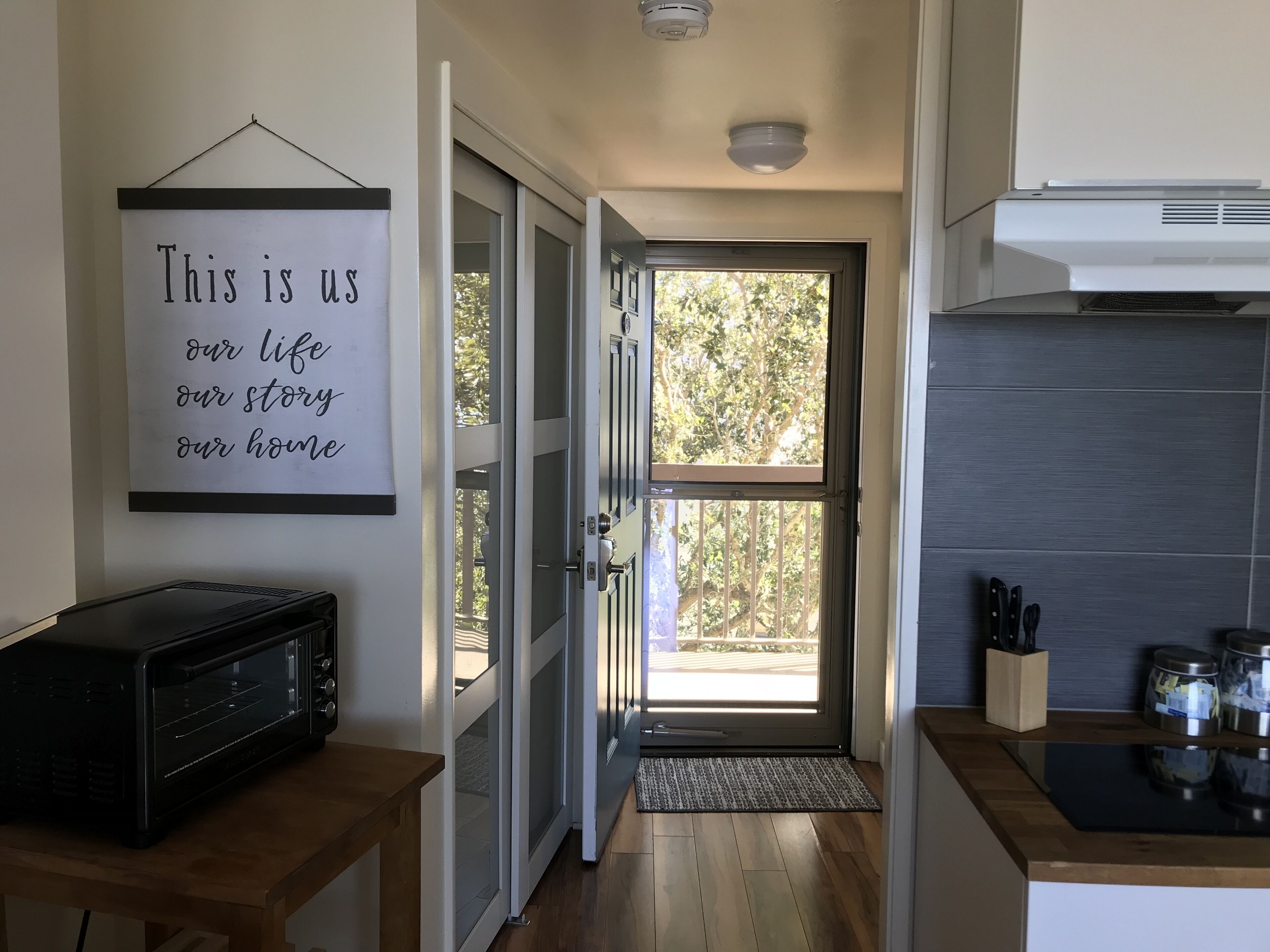 A kitchen with a microwave, a door with a glass panel, and a sign on the wall.