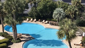A large, curved swimming pool surrounded by palm trees and lounge chairs. - PERFECT VIEW!!! Waterfront, Marina and 2 Pools! (Fort Walton Beach)