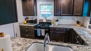 A kitchen with dark wooden cabinets, a stainless steel sink, a stove, and a window above the sink. - 2-Bedroom, Dog Friendly Home sleeps 6 on the Tennessee River/Chickamauga Lake (Decatur)