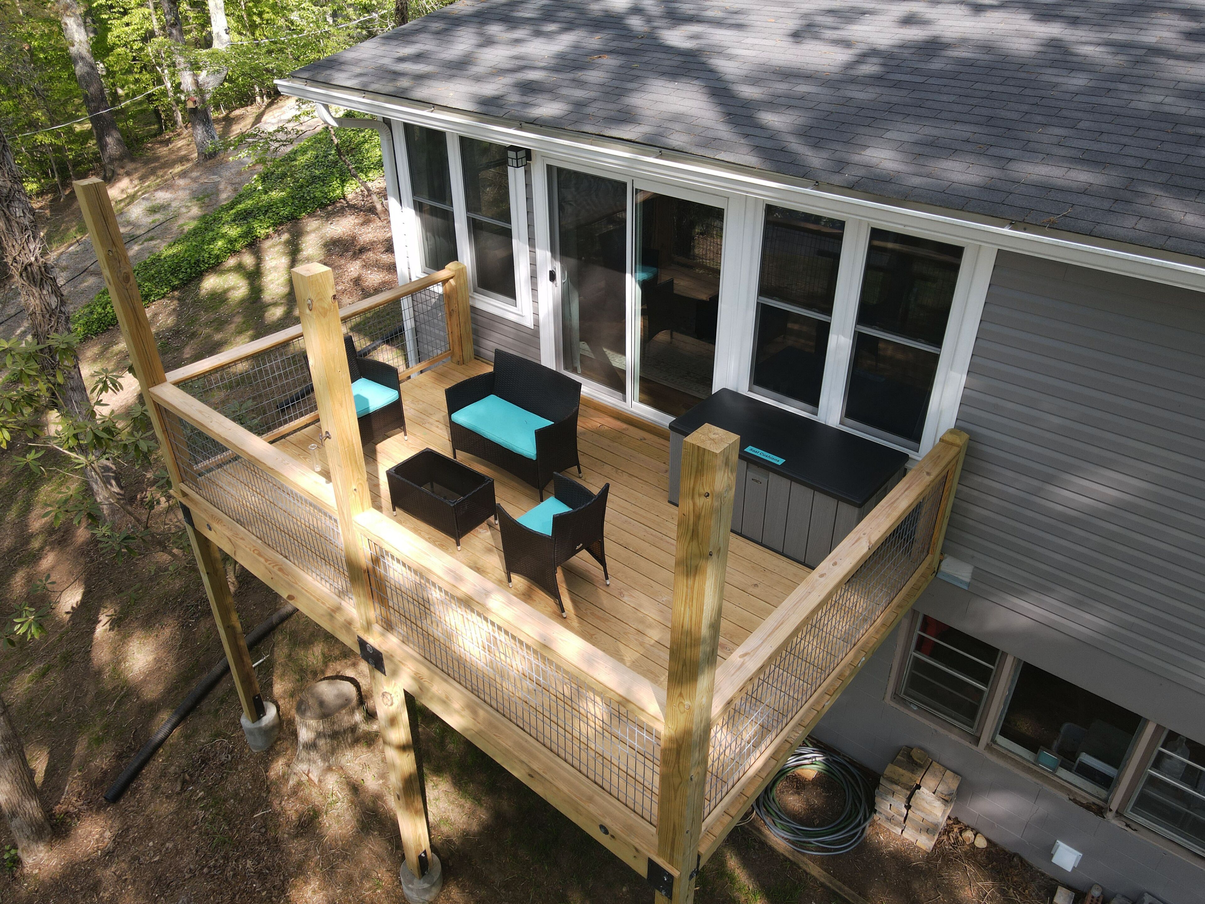 A wooden deck with outdoor furniture, a covered area, and a house with large windows.