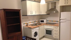 Cocina compacta con lavadora, microondas, horno y refrigerador.