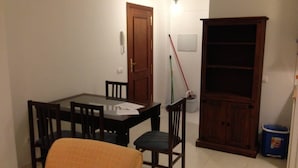 Un comedor con una mesa y sillas de madera, un armario y una escoba.