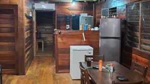 A wooden cabin interior with a dining area, kitchenette, and ceiling fans. - Belize Blue Hole Tropical Cabin for Scuba divers! (Lighthouse Reef)