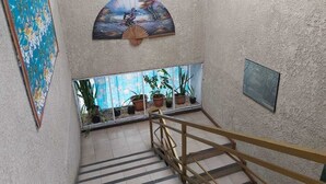 Un escalier avec une rampe en bois, une fenêtre ornée de plantes en pot et un tableau accroché au mur.