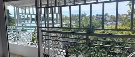 A balcony with metal railings and a view of a residential area with houses and greenery.