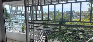 Un balcón con barandilla de metal y vista a una zona residencial con casas y vegetación.