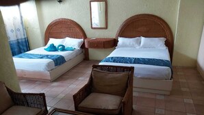 Une chambre d’hôtel avec deux lits, une petite table et une chaise en osier.