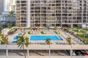 A high-rise hotel with a rooftop pool, sun loungers, and a view of the cityscape.