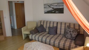 Una sala de estar con un sofá de cuadros, una silla, una mesa y un cuadro en la pared.