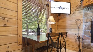 A wooden interior with a table and chairs, a lamp, a bottle, and a sign for RENTBR INSON.COM.