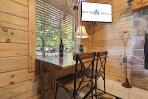 Un intérieur en bois avec une table et des chaises, une lampe, une bouteille et une enseigne indiquant RENTBR INSON.COM.