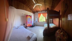 Ein Zimmer mit zwei Betten, einem Deckenventilator und einem fensterbepflegten Fenster.