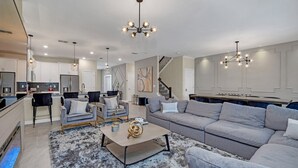 Ein modernes Wohnzimmer mit einem grauen Sofa, einem Couchtisch und einer Chandelüster.