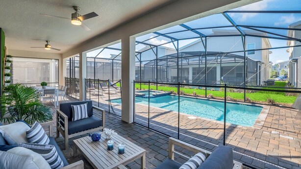 Eine überdachte Terrasse mit Pool, Gartenmöbeln und Blick auf eine Wohngegend.