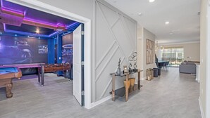 Ein modernes Wohnzimmer mit einem Kicker, einem Glastisch und einem Essbereich mit einer Chandelier.