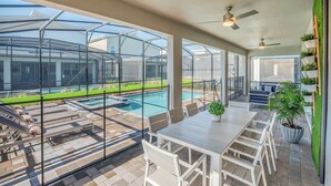 Ein überdachter Patio mit Pool, Sitzgelegenheiten im Freien und Essbereich.