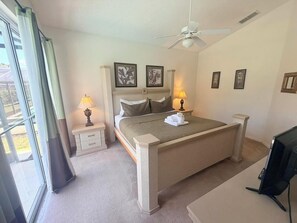 Ein Schlafzimmer mit einem Bett, Nachttischen, einem Deckenventilator und einem Fernseher.