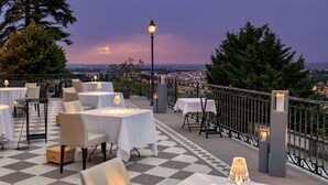 An outdoor terrace with tables and chairs, a view of the city, and a railing. - Villa La Bollina (Serravalle Scrivia)