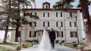 A couple walking towards a large building with multiple windows and balconies. - Villa La Bollina (Serravalle Scrivia)