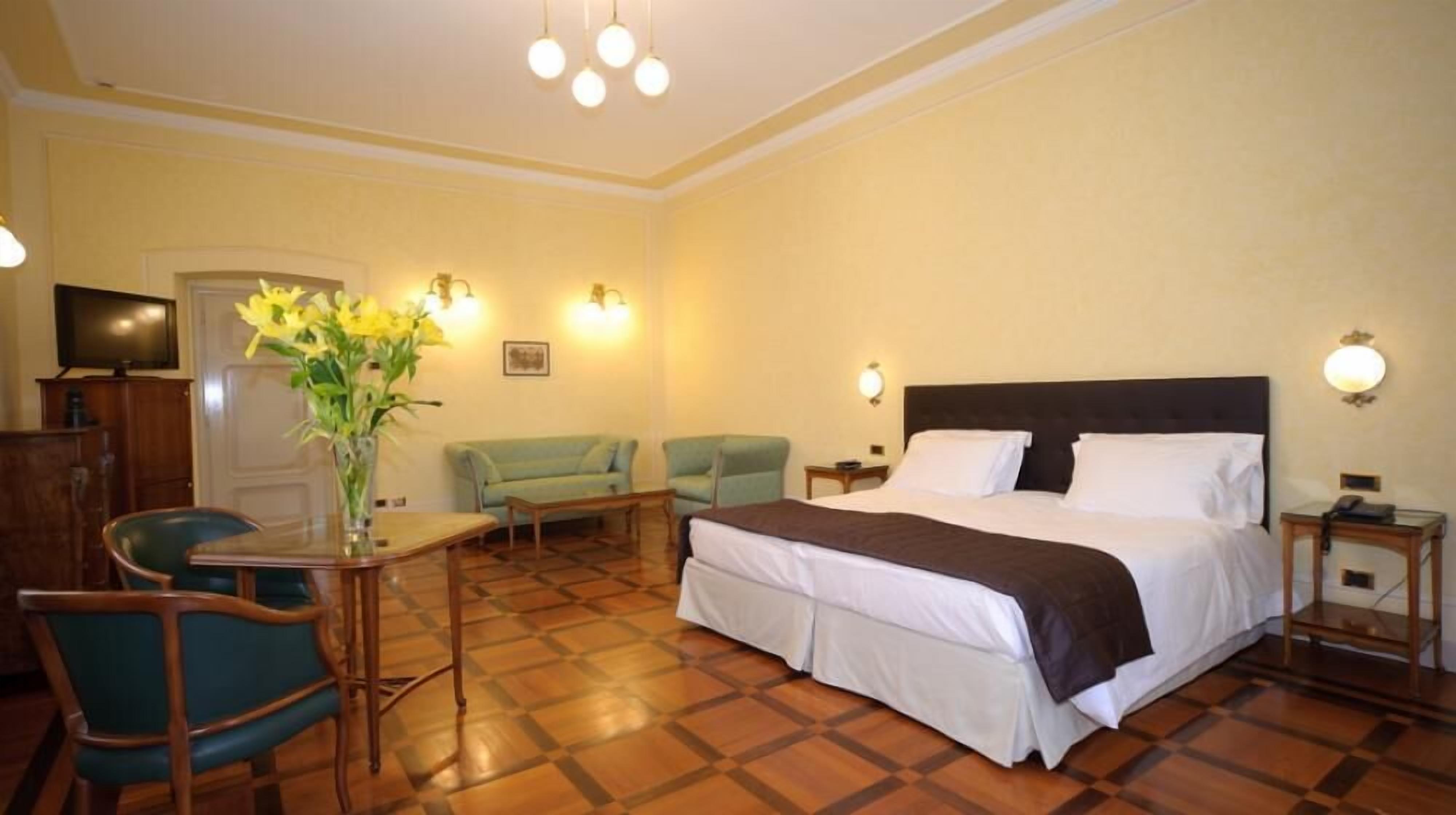 Habitación de hotel con una cama grande, dos sillones, una mesita y un televisor.