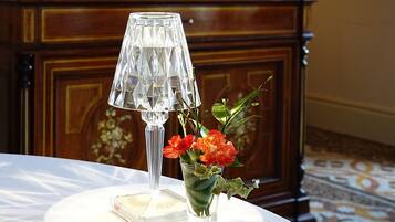 Ein Tisch mit einem klaren Glaslaternenfuß und einer kleinen Vase mit Blumen.