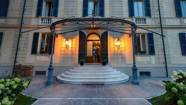 A grand entrance with a covered staircase leading to a door, flanked by two illuminated wall sconces. - Villa La Bollina (Serravalle Scrivia)