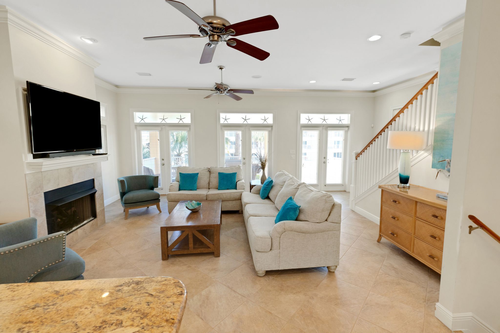 A spacious living room with a fireplace, two sofas, a coffee table, and a TV mounted on the wall.