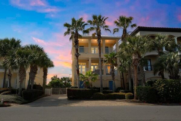 A multi-story hotel with a central courtyard, palm trees, and a balcony on the second floor.