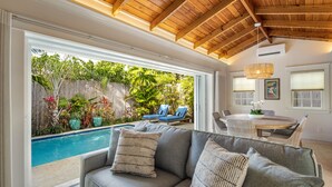 Un salon moderne avec un canapé gris, une table à manger et une vue sur la piscine.
