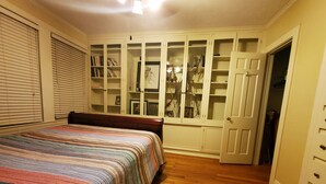 A bedroom with a bed, wooden flooring, a built-in closet with glass doors, and a door leading to another room. - Downtown Historic district at Cascades Park, Best location (Tallahassee)