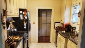 A compact kitchen with white cabinets, a black refrigerator, and a stove. There is a window with blinds and a microwave on the counter. - Downtown Historic district at Cascades Park, Best location (Tallahassee)