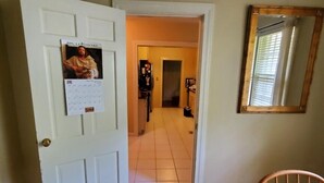 A room with a wooden floor, a white door with a calendar, a mirror, and a dining table with chairs. - Downtown Historic district at Cascades Park, Best location (Tallahassee)