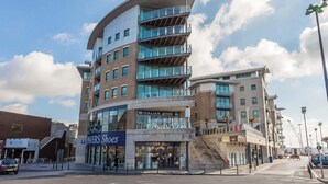 A multi-story building with a modern architectural design, featuring a prominent curved facade and multiple balconies. - Tally Ho -Parking and Wi-Fi included (Poole)