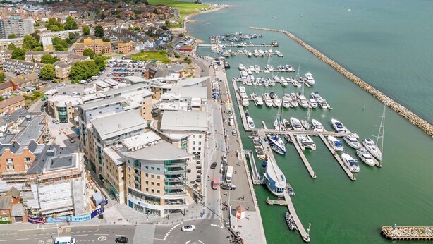 An aerial view of a coastal town with a marina, buildings, and a road. - Tally Ho -Parking and Wi-Fi included (Poole)