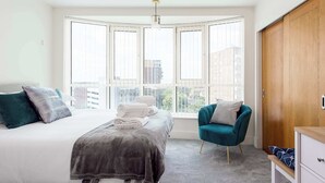 A bedroom with a bed, a chair, a wardrobe, and large windows. - Tally Ho -Parking and Wi-Fi included (Poole)
