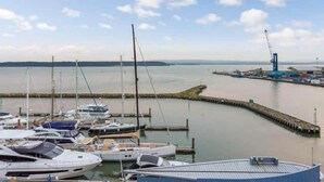 A marina with boats docked, a pier extending into the water, and a distant industrial area. - Tally Ho -Parking and Wi-Fi included (Poole)