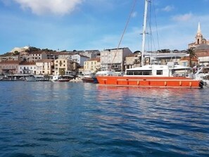 A harbor with a large orange boat docked, buildings in the background, and a clear sky. - House 40m² large organic garden 200m Calvi beach (Calvi)