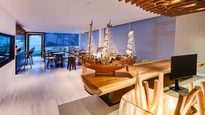 A modern interior with a wooden ship model, a dining area, and a large window offering a view. - Seasalter Maldives (Hulhumalé)