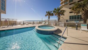 Une piscine avec un jacuzzi, des chaises longues et des palmiers.