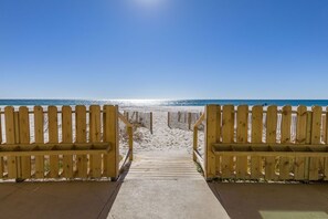 A wooden pathway leading to a beach with a clear sky.